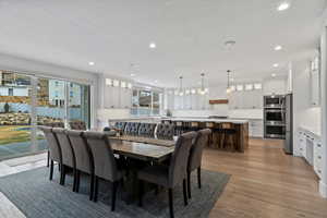 Dining space featuring light wood-type flooring, a textured ceiling, and recessed lighting