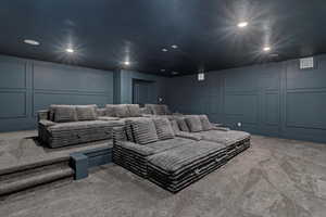 Carpeted home theater featuring a decorative wall and recessed lighting