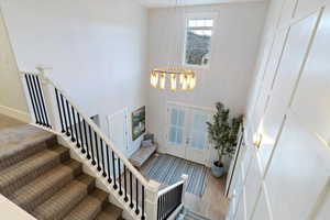 Foyer with stairway, french doors, a towering ceiling, a chandelier, and wood finished floors