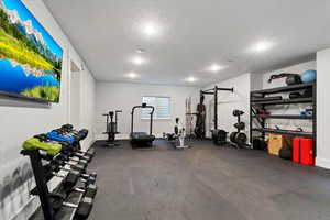 Workout area featuring dark flooring, a textured ceiling, and recessed lighting