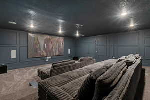 Carpeted cinema with a decorative wall, a textured ceiling, and recessed lighting