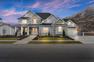 Craftsman house featuring board and batten siding, covered porch, driveway, a standing seam roof, and a yard