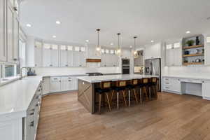 Kitchen with glass insert cabinets, white cabinets, a kitchen island, open shelves, and a breakfast bar area