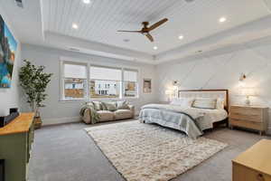 Carpeted bedroom with wood ceiling, a ceiling fan, a tray ceiling, and recessed lighting