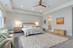 Bedroom with wooden ceiling, carpet, a raised ceiling, a decorative wall, and ceiling fan