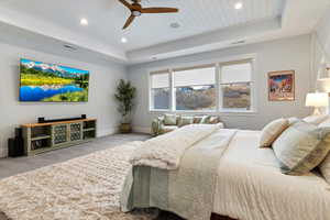 Carpeted bedroom with a tray ceiling, ceiling fan, and recessed lighting