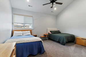 Carpeted bedroom with lofted ceiling, ceiling fan, and radiator heating unit