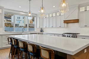 Kitchen featuring glass insert cabinets, white cabinets, tasteful backsplash, pendant lighting, and recessed lighting