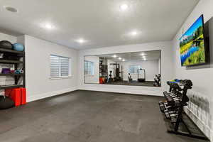 Workout room with dark flooring, a textured ceiling, and recessed lighting