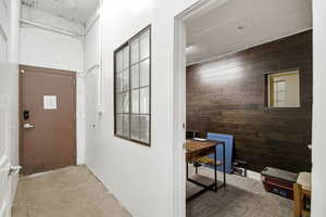 Foyer with wooden walls, concrete flooring, and an accent wall
