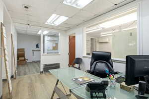 Home office featuring a paneled ceiling, wood finished floors, and a wall mounted AC
