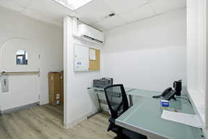Office area featuring a wall mounted AC and a drop ceiling