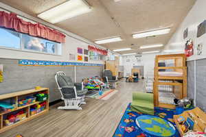 Playroom featuring a textured ceiling, wood walls, and wainscoting
