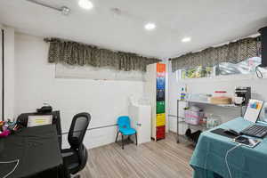 Bedroom with concrete block wall, light wood-style flooring, and recessed lighting