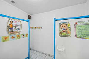 Bathroom with a textured ceiling, tile patterned floors, and ornamental molding