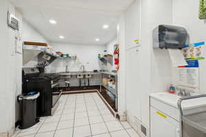 Kitchen featuring range with gas cooktop, light tile patterned flooring, white cabinetry, recessed lighting, and light countertops