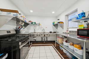Kitchen featuring stainless steel gas stove, light tile patterned floors, black microwave, and recessed lighting