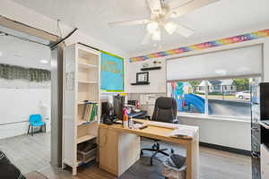 Office area featuring a textured ceiling, a ceiling fan, and a wainscoted wall