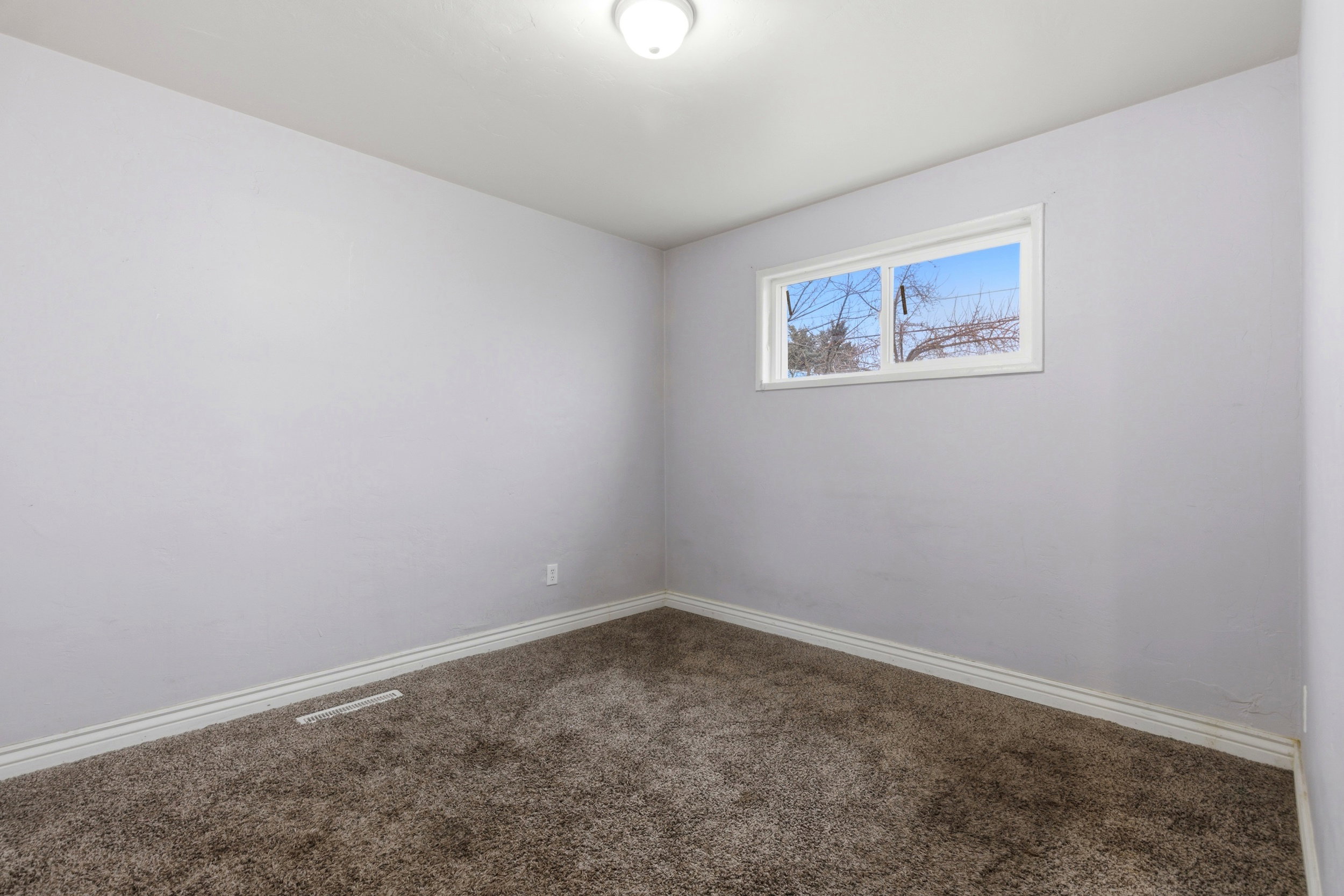 Spare room with dark colored carpet and baseboards
