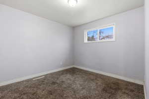 Spare room with dark colored carpet and baseboards