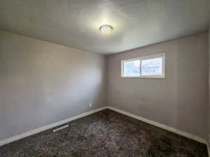 Unfurnished room featuring dark carpet and baseboards