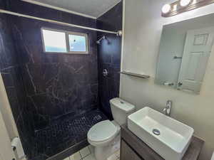 Full bath featuring a marble finish shower, vanity, and tile patterned flooring