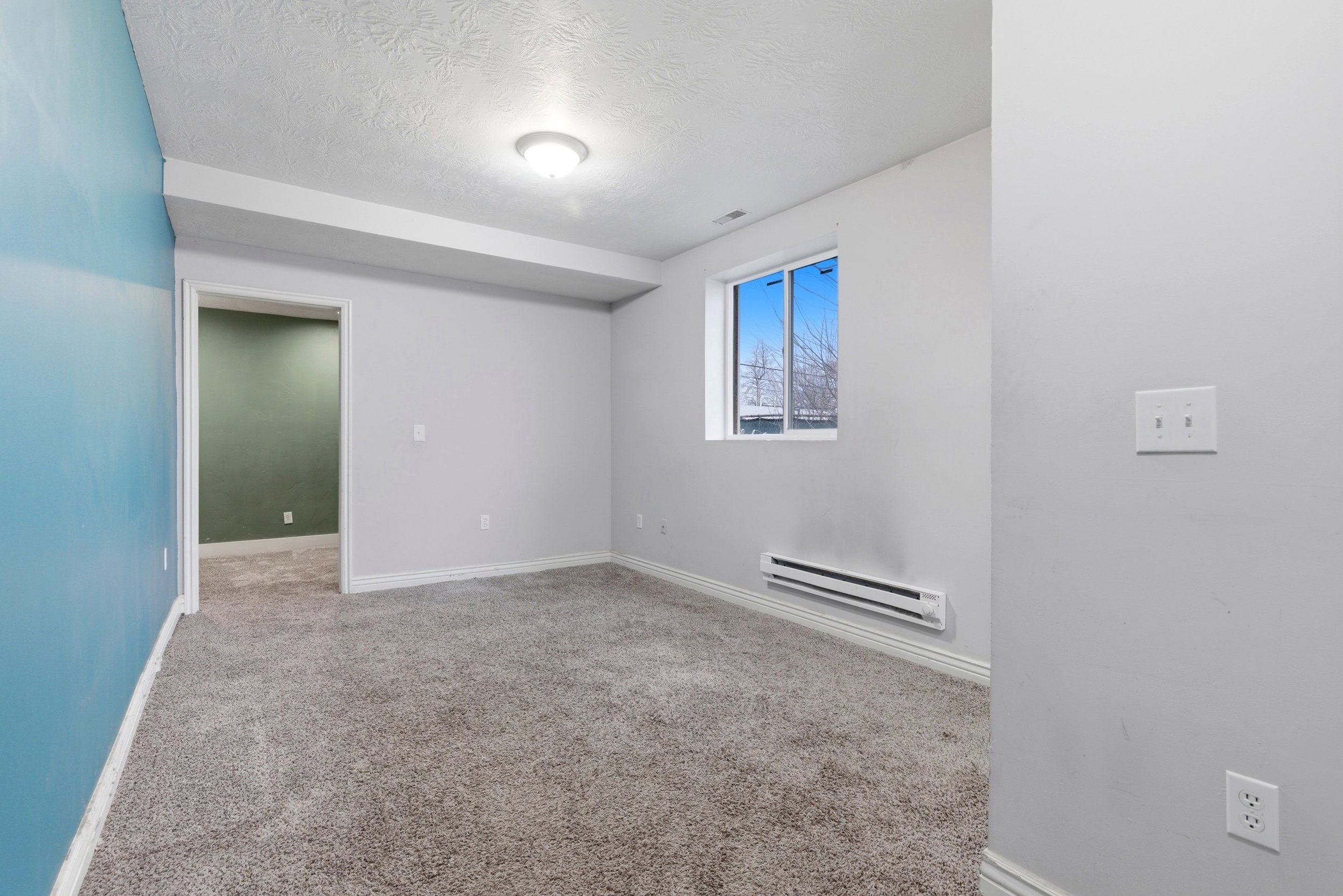 Unfurnished room with a baseboard heating unit, a textured ceiling, and light carpet