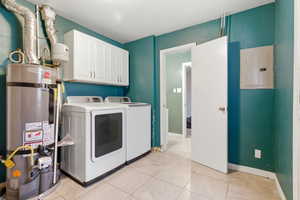 Laundry area featuring cabinet space, electric panel, water heater, washing machine and dryer, and light tile patterned floors