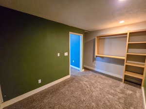 Unfurnished bedroom featuring dark carpet and a textured ceiling