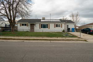 Ranch-style house featuring solar panels and a fenced front yard