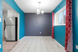 Unfurnished dining area featuring suspended lighting and light tile patterned floors
