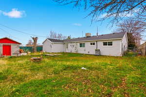 Back of house with an outdoor structure, a shingled roof, and a gate