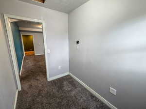 Unfurnished room featuring dark colored carpet and a textured ceiling