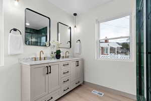 Bathroom featuring double vanity, light wood-style flooring, and a shower with shower door