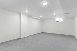 Basement with a textured ceiling, light colored carpet, and recessed lighting