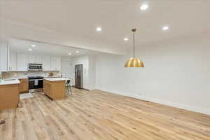 Kitchen featuring recessed lighting, stainless steel appliances, a kitchen breakfast bar, backsplash, and a kitchen island