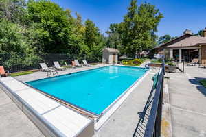 Community pool with a patio area and a storage unit