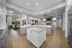 Kitchen with gray cabinets, open floor plan, high end appliances, a stone fireplace, and recessed lighting