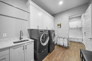 Laundry area featuring dark wood-style flooring, independent washer and dryer, and cabinet space