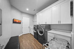 Laundry room with cabinet space, dark wood-type flooring, recessed lighting, separate washer and dryer, and electric panel