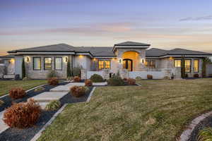 View of front of property featuring a yard, stucco siding, and stone siding