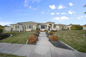 Prairie-style home with a front yard, stone siding, and stucco siding
