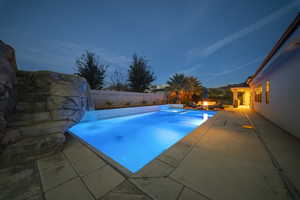 Pool at dusk featuring a fenced backyard, a patio area, and an outdoor fire pit