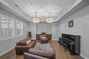 Living area featuring a tray ceiling, wood finished floors, and a chandelier
