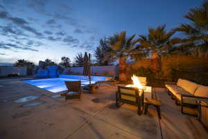 Pool at dusk with a fenced backyard, a patio area, and an outdoor living space with a fire pit