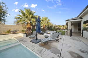 View of swimming pool featuring an outdoor living space with a fire pit, a patio area, a fenced backyard, and an in-ground hot tub