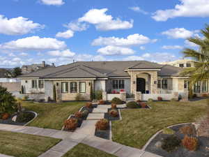 View of front of property with stone siding, a front lawn, stucco siding, and a tile roof