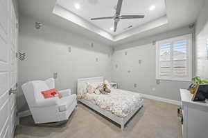Bedroom with a raised ceiling, recessed lighting, and ceiling fan
