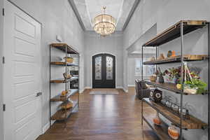 Entryway featuring dark wood-style flooring, a chandelier, and a towering ceiling