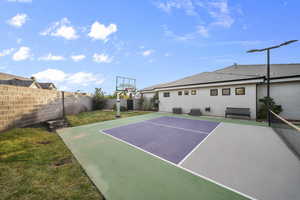 View of sport court featuring a fenced backyard and basketball hoop